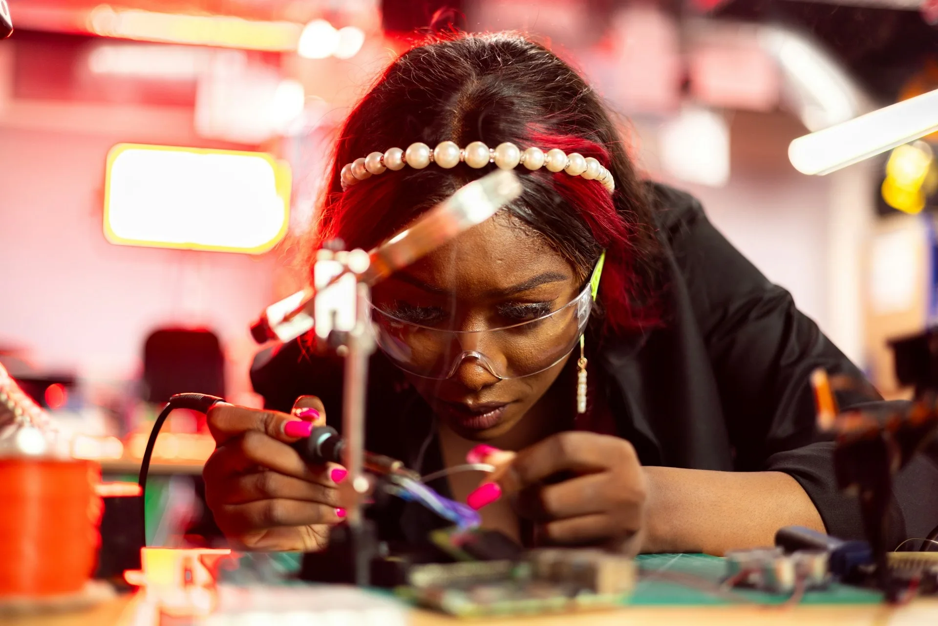 Student wearing safety goggles soldering electronics in a lab, representing hands-on training at trade schools for women.